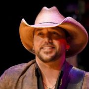 A young Jason Aldean, guitar strapped across his chest, belts out a tune at a dusty Georgia talent show, hints of stardom already glinting in his eyes