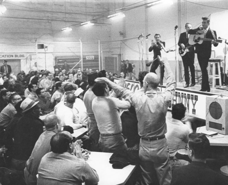 Johnny Cash strums his guitar while performing onstage at Folsom State Prison
