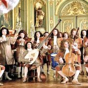An ornate violin resting on sheet music with Baroque era motifs